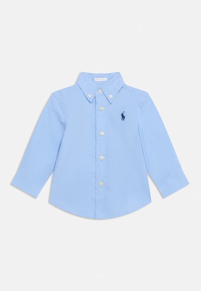 Ανοιχτό μπλε μπλουζάκι με μακριά μανίκια για νήπιο με γιακά με κουμπιά και κουμπιά μπροστά, με μικρό σκούρο μπλε κεντημένο λογότυπο στο στήθος.