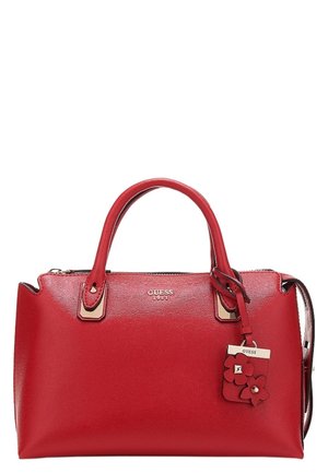 Czerwona torebka Guess z podwójnymi uchwytami, zamknięciem na suwak oraz małą ozdobą w kształcie kwiatu przymocowaną u góry.