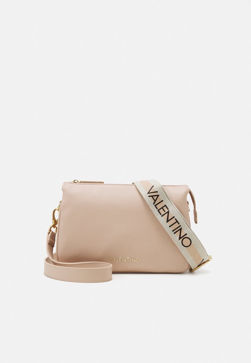 Brosková crossbody taška z faux kůže se zlatými detaily, zipovým uzávěrem a nastavitelným popruhem, na kterém je tučným písmem uvedený název značky.