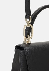 Coin de sac à main en cuir noir texturé avec fermoir en métal doré et sangle d'épaule ajustable attachée.