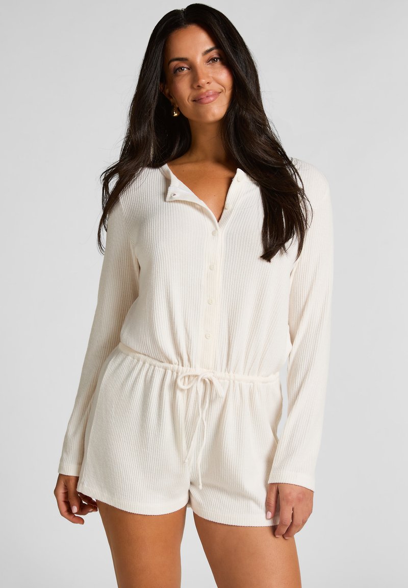 Mono blanco acanalado con mangas largas, escote tipo henley abotonado, cintura elástica y detalle de cordón. Tejido suave con acabado texturizado.