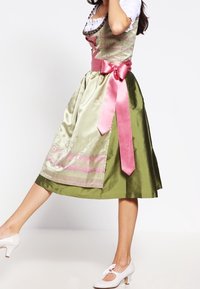 Perinteinen dirndl-mekko, jossa on vihreä satiinihame, vaaleanvihreä liivi vaaleanpunaisilla yksityiskohdilla ja leveä vaaleanpunainen nauha solmittuna vyötärölle.