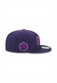 Purple cap with a flat brim, featuring embroidered text and a logo on the side. The underside of the brim has a patterned texture.