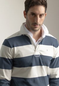 Camisa polo de manga larga con rayas horizontales en azul marino y blanco, un cuello blanco y una botonera con un pequeño logo bordado.