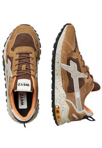 Zapatillas de gamuza marrón y beige con un acento de diseño blanco, entresuela beige salpicada, suela de goma negra y detalles interiores en color naranja.