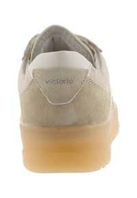 Sneaker in camoscio e pelle beige con suola in gomma traslucida, linguetta del tallone visibile con il marchio "victoria", vista da dietro.