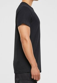 Černé bavlněné tričko s krátkými rukávy, kulatým výstřihem, volným střihem a hladkým povrchem. Bez viditelných vzorů nebo log.