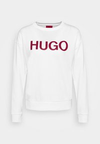 Sweat-shirt blanc à manches longues avec le texte rouge "HUGO" centré sur le devant, doté d'un col rond et de poignets et ourlet côtelés.