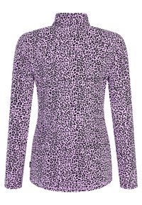 Top de manga larga en una tela de color rosa claro con estampado de leopardo negro, cuello alto y forma ajustada. Textura suave y elástica.