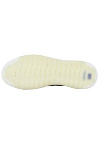 Semelle extérieure en caoutchouc blanc avec une surface texturée, dotée de plusieurs trous de drainage et d'un bord lisse. Semelle intermédiaire noire avec un détail de marque discret.