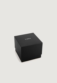 Čierny štvorcový box vyrobený z pevných materiálov s hladkým povrchom. Na viečku sú biele písmená s nápisom "TIMEX".