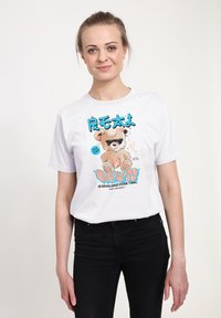 Witte katoenen t-shirt met een kleurrijke cartoonbeer in de afbeelding met een zonnebril, aangevuld met tekst in blauw en oranje die leest: "wordt in de loop van de tijd ontwikkeld."