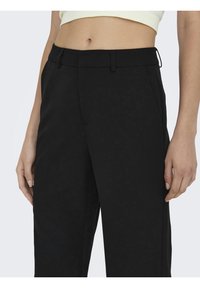 Svarta tapered byxor med en jämn textur, bältesloopar och sidofickor. Designen är minimalistisk med en skräddarsydd passform.