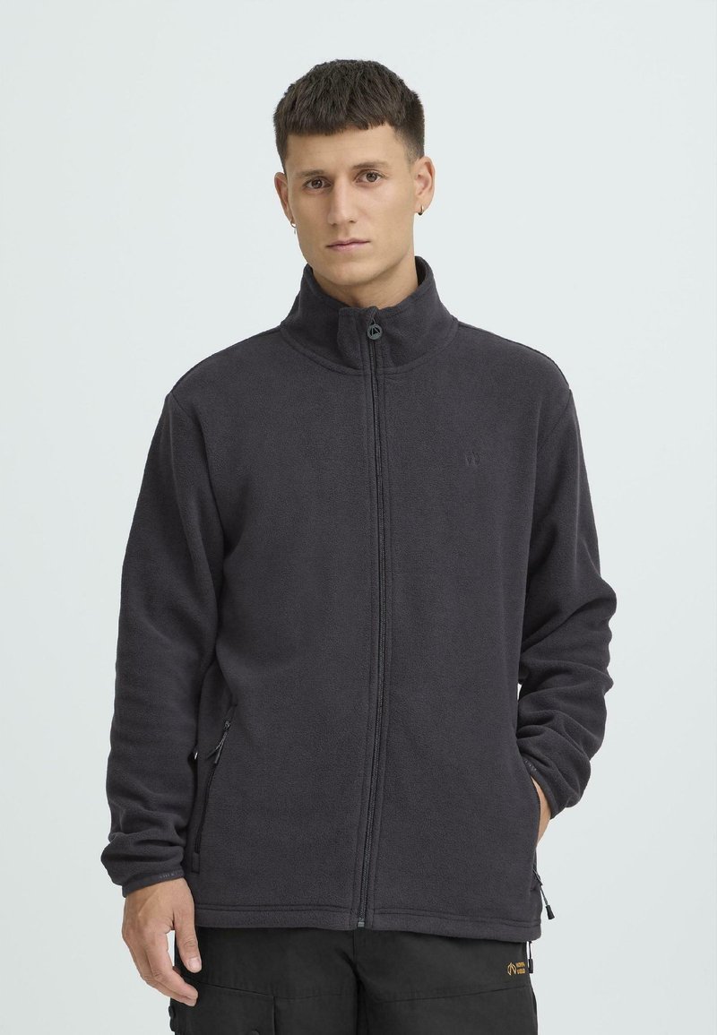 Tumehall fliisjakk kõrge kraega, täis tõmblukuga, küljetaskute ja pehme tekstuuriga. Rinnal minimaalne bränding.