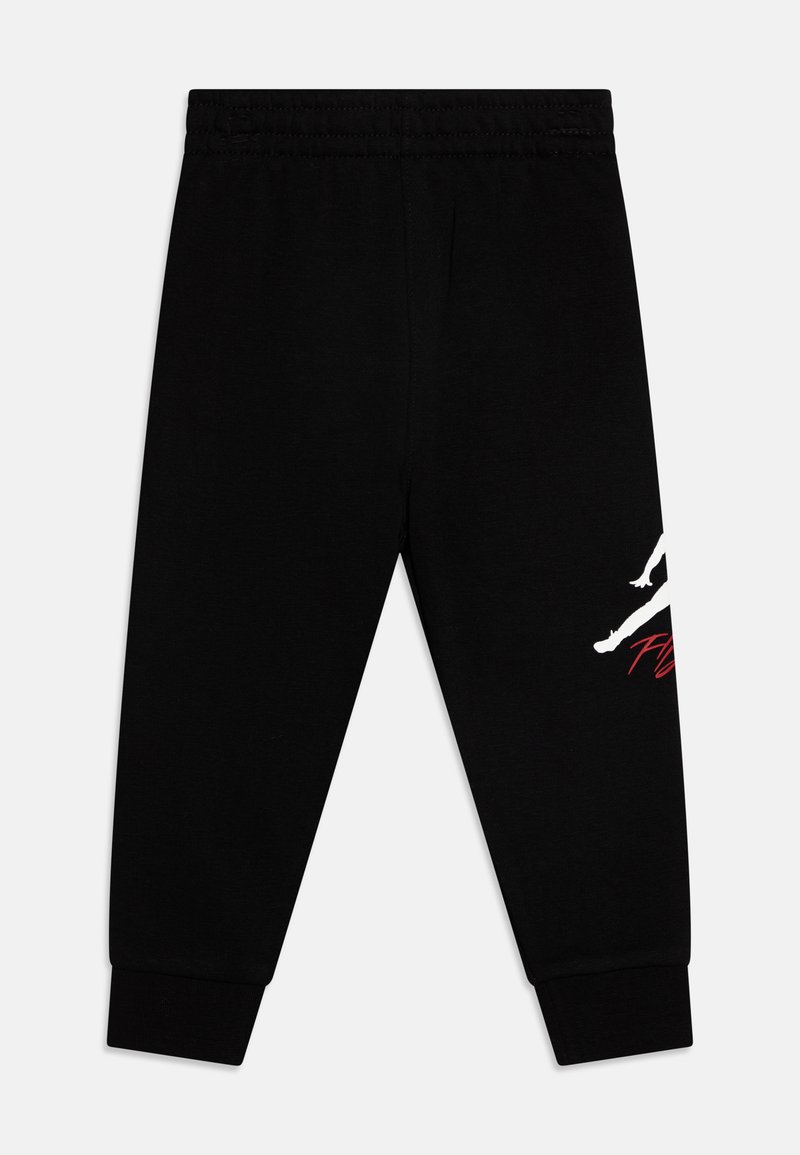 Pantalon de jogging noir en coton, équipé d'une taille élastique, de poignets fuselés et d'un design graphique blanc avec des accents rouges sur une jambe.