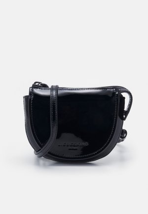 Petit sac bandoulière noir en cuir verni avec forme arrondie, fermeture éclair et sangle réglable sur fond blanc.