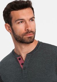 Tmavě šedé tričko henley s burgundským zapínáním na knoflíky a třemi černými knoflíky, s jemnou a hladkou texturou a kulatým výstřihem.