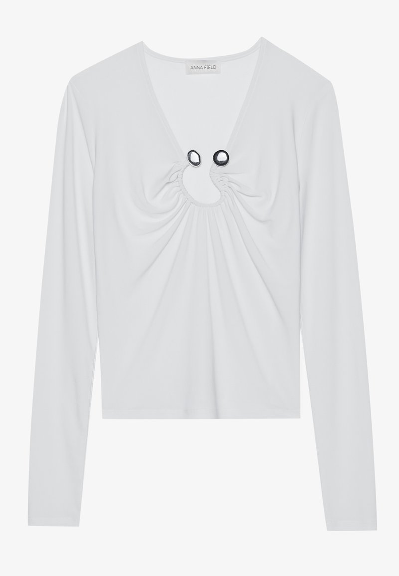 Maglietta bianca a maniche lunghe con scollatura a V profonda, caratterizzata da tessuto arricciato attorno al collo e due accenti circolari neri.