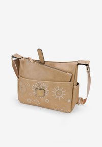 Bolso cruzado de cuero en color beige con intrincados patrones de bordado blanco, cierre superior con cremallera, correa ajustable y un bolsillo frontal.