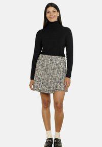 Čierny rolák v kombinácii s béžovou a čiernou tweedovou mini sukňou, ktorá má akcent pracky, doplnená tmavými mokasínami a bielymi ponožkami.