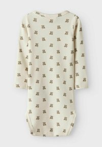 Ribbat långärmad bodysuit i krämfärg med ett upprepande mönster av bruna nallebjörnar. Har rund halsringning och tryckknappsstängning i botten.