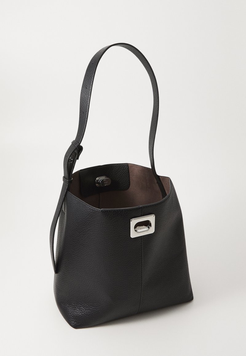 Sac seau en cuir noir avec une bandoulière réglable et un fermoir rectangulaire argenté sur un fond clair uni.