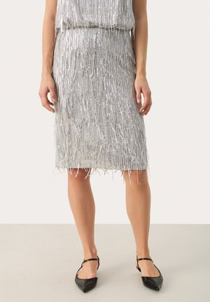 Silver fringe knee-length skirt with a textured surface, featuring long, metallic strands and a fitted silhouette. Paired with black pointed flats.