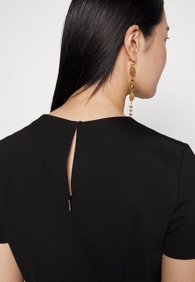 Robe noire à manches courtes, avec une ouverture en forme de clé au dos. Texture de tissu lisse et fermeture éclair dissimulée.
