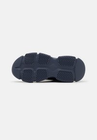 Suela de zapato de goma en un azul marino oscuro con un patrón de banda de rodadura texturizado que presenta surcos en zigzag y acentos circulares para mayor tracción.