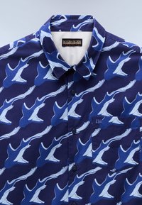 Chemise bleu marine à boutons avec motif baleine bleu clair et blanc, poche poitrine avec petit détail drapeau et col pointu.