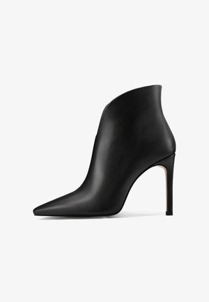 Stivale in pelle nera alla caviglia con punta affusolata e alto tacco a spillo, caratterizzato da una superficie liscia e un design minimalista senza hardware visibile.