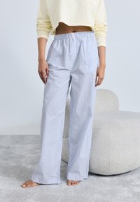 Φαρδιά παντελόνια με ανοιχτό μπλε ρίγες από απαλό ύφασμα, με ελαστική μέση, συνδυασμένα με ένα κίτρινο cropped φούτερ.