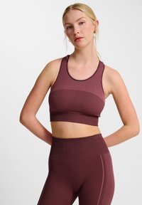 Bourgondische sportbeha met ribbeltextuur en brede bandjes. Het heeft een naadloos ontwerp en is gecombineerd met bijpassende high-waisted leggings.