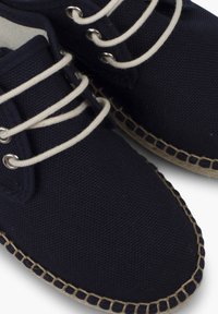 Námořnické plátěné boty s kulatou špičkou, zdobené béžovými tkaničkami a prošíváním, s texturovaným povrchem a detaily juty na podrážce.