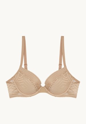 Soutien-gorge en dentelle de couleur nude avec des bonnets moulés, des bretelles réglables et des motifs géométriques le long des bords. Tissu doux avec une finition texturée.