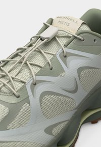 Ανοιχτό πράσινο και μπεζ αθλητικό παπούτσι Merrell Matis με πλέγμα στην επάνω επιφάνεια, συνθετικές επικαλύψεις και ελαστικά κορδόνια που στερεώνονται με πλαστικό κουμπί.
