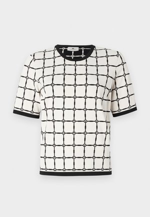 Top à manches courtes en crème avec un motif géométrique noir, comportant un col rond noir et des accents en tissu texturé.