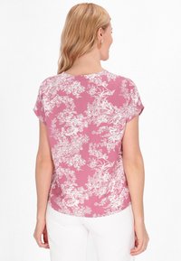 Blusa floreale a maniche corte con uno sfondo rosa e stampe botaniche bianche, tessuto morbido, scollatura rotonda e vestibilità comoda.
