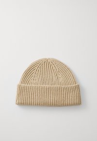 Bonnet en tricot de couleur beige clair avec une texture côtelée et un revers replié. Top arrondi et finition lisse, adapté à un usage par temps froid.