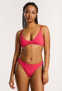 Rosa Bikini-Set mit strukturiertem Muster, verstellbaren dünnen Tr�ägern am Oberteil und minimaler Bedeckung am Unterteil. Glatte Stoffoberfläche.