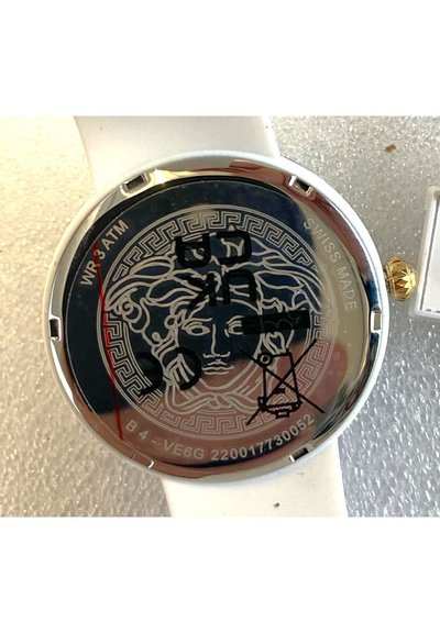 Montre à quartz avec un bracelet en silicone blanc et un boîtier rond en argent. Le dos présente un design Medusa noir avec des détails gravés, y compris "SWISS MADE".