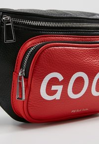 Sac en cuir texturé noir et rouge avec des fermetures éclair argentées, affichant partiellement un texte blanc "GOO" et un petit nom de marque imprimé PS Paul Smith.