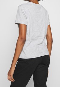 T-shirt grigia a maniche corte vista da dietro, realizzata in tessuto morbido con una texture liscia, presenta un colletto rotondo classico e un taglio dritto.