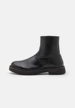 Sorte lær ankle boots med en glat tekstur, rund tå og elastiske sideløsninger; kraftig gummisål for ekstra holdbarhed.