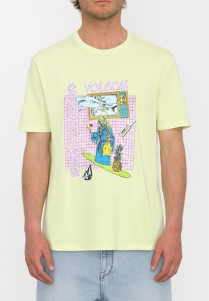 Camiseta de manga corta verde claro con un vibrante estampado gráfico que presenta un tiburón, un personaje y íconos sobre un fondo de rejilla rosa. Tejido de algodón suave.