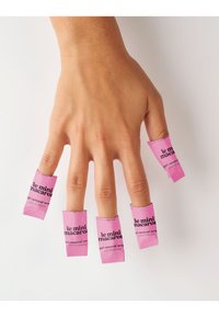 Les enveloppes de retrait de gel Le Mini Macaron en rose vif sur cinq doigts d'une main, avec un texte noir et un design rectangulaire pour une application facile.