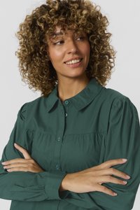 Dark green button-up blouse with a collar, full sleeves, and gathered detail across the bust. Soft fabric texture, casual design.