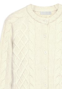 Krēmkrāsas diegu adīta kardigāna jaka ar apaļu kakla izgriezumu, sešām pogām priekšpusē un strukturāliem rakstiem visā jakā. Mīksts, silts audums.