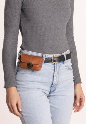 Bruine leren tas bevestigd aan een zwarte riem, gedragen om de taille. Lichtblauwe spijkerbroek met een hoge taille en een grijze top met lange mouwen met ribbelmotief.