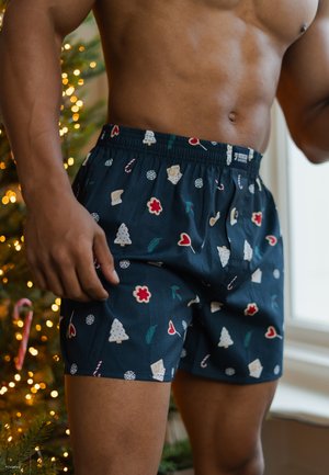 Boxers navy avec un motif festif comportant des arbres, des cœurs, des bonbons et des fleurs ; taille élastique ; texture de tissu douce.